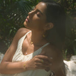 Close-up of a model wearing the Transformed by Love Lotus Bracelet in a serene outdoor setting, highlighting its spiritual significance. The bracelet, made with rose quartz, serves as a meaningful accessory for yoga and meditation, representing protection and the energy of the sun and moon.