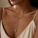Gold lariat necklace with lotus flower pendant and dangling rose quartz stone on adjustable chain.