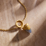 The Guiding Spirit Labradorite and White Topaz Lotus Locket Necklace resting on a smooth surface, representing spiritual jewelry that inspires transformation and supports the journey of manifestation and meditation.