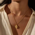 Close-up of a model wearing the Gaining Clarity White Topaz and Mother of Pearl Hamsa Reversible Necklace, illustrating its role as a spiritual talisman. This exquisite jewelry piece symbolizes protection and meaningful meditation, perfect for those embracing their spiritual journey under the sun and moon.