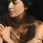 Model wearing the Celestial Balance Yin Yang White Topaz Necklace, showcasing its elegant design amidst a serene outdoor setting. This meaningful piece of spiritual jewelry embodies protection and the zodiac's significance in guiding one's path.