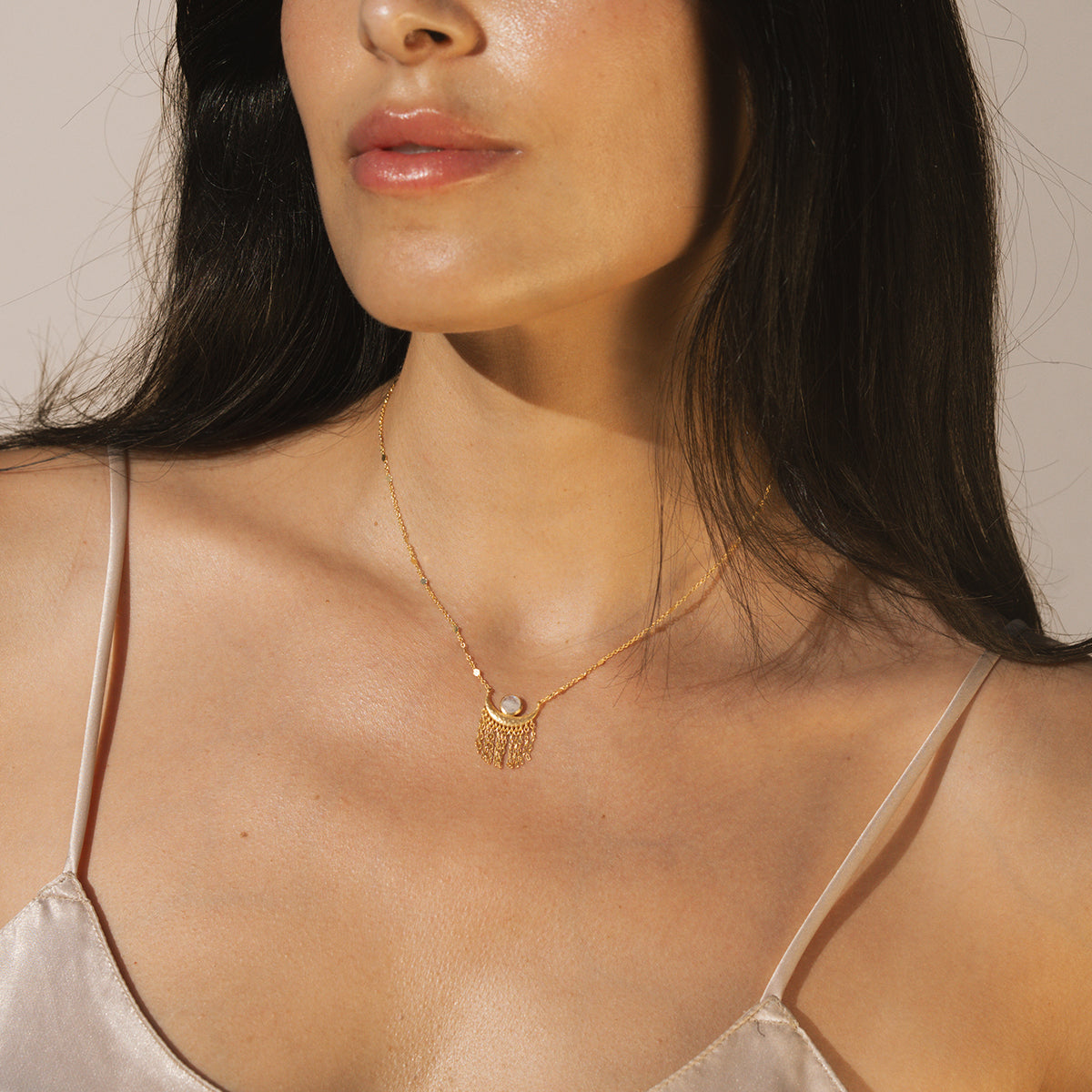 A woman wearing the Cascade of Starlight Moonstone Fringe Necklace, showcasing its elegant design around her neck. This spiritual piece enhances her meditation practice while symbolizing meaningful connections to the sun, moon, and zodiac, perfect for yoga enthusiasts.