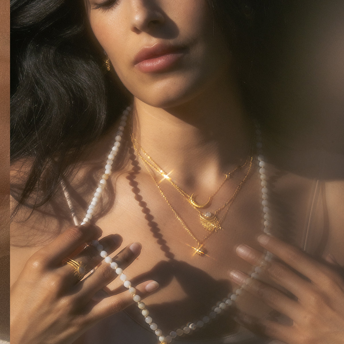 Close-up of a woman adorned in layered necklaces, including the Cascade of Starlight Moonstone Fringe Necklace. This spiritual jewelry represents femininity, protection, and manifestation, ideal for those on a journey of yoga and meditation to enhance their spiritual meaning.