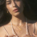 A woman showcasing layered necklaces including the Clarity White Topaz Starburst Necklace, embodying the essence of meaningful spiritual jewelry for meditation, protection, and inspirational talismans.