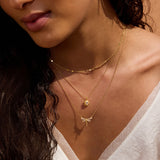 Gold-toned necklace with layered chains and a star-shaped crystal pendant worn on person's neck.