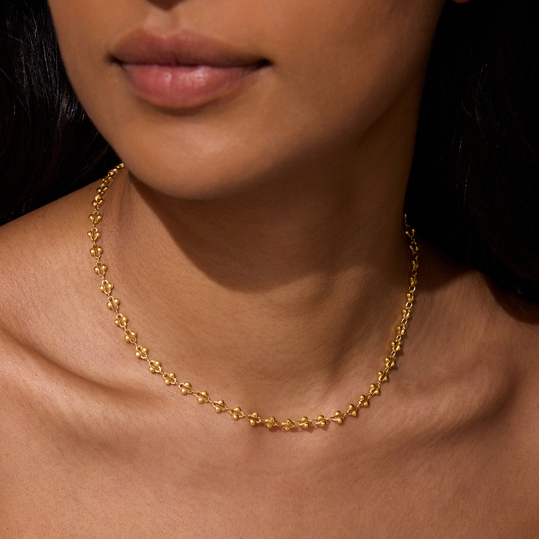A close-up of a model wearing the Golden Hour Coin Chain Necklace, showcasing its elegant 16" length with a 3" extender. This stylish piece of spiritual jewelry enhances your yoga practice, representing the sun and moon's balance in spiritual meaning and manifestation.