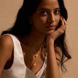 Close-up of a model wearing multiple layers of jewelry, including the Journey to Love Moonstone Lotus Heart Necklace, embodying a blend of spiritual aesthetics. This necklace serves as a talisman for those interested in yoga and zodiac meanings, enhancing spiritual connections and manifestations.