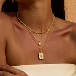 Gold-toned layered necklaces with textured chain, small round pendant, and rectangular sun pendant on white background.