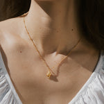 Gold-toned conch shell pendant on delicate chain necklace worn close to neck.