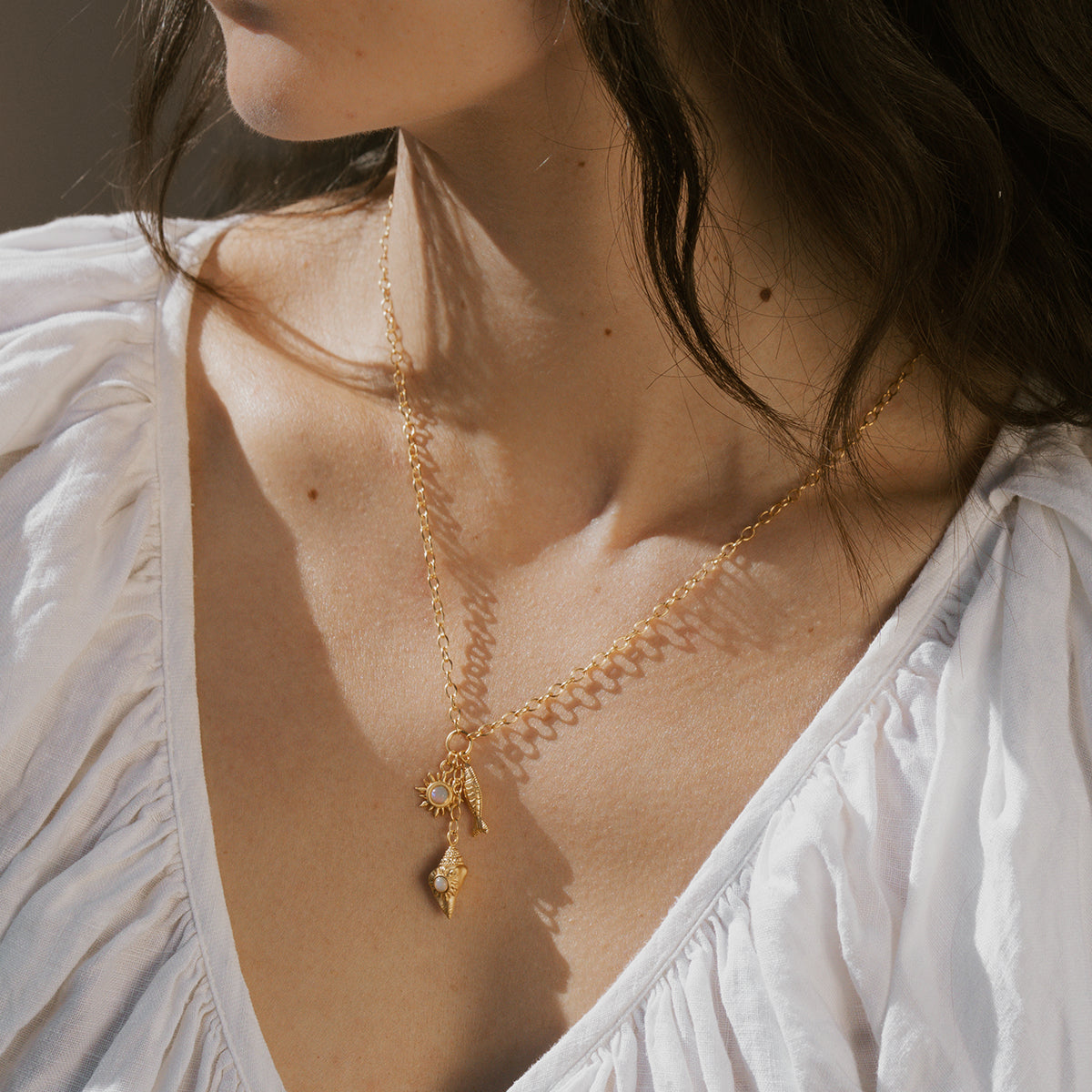 Gold chain necklace with shell and starfish charms hanging from delicate links.
