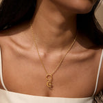 A close-up view of a woman wearing the Infinite Possibilities Moonstone Celestial Charm on a delicate gold necklace. This elegant piece combines the sun and moon motifs, embodying spiritual significance and serving as a powerful talisman for manifestation and protection in a meaningful yoga practice.
