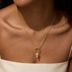 A close-up of the Honor Your Faith Cross Charm pendant, featuring an 18kt gold plated cross with a brilliant white topaz. This piece exemplifies spiritual jewelry, serving as a meaningful talisman for meditation and manifestation, perfect for yoga practices, while invoking protection and connection to the sun and moon.