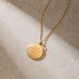 A gold necklace with a round pendant engraved "For the children of Pradiya" rests on a beige stone surface.