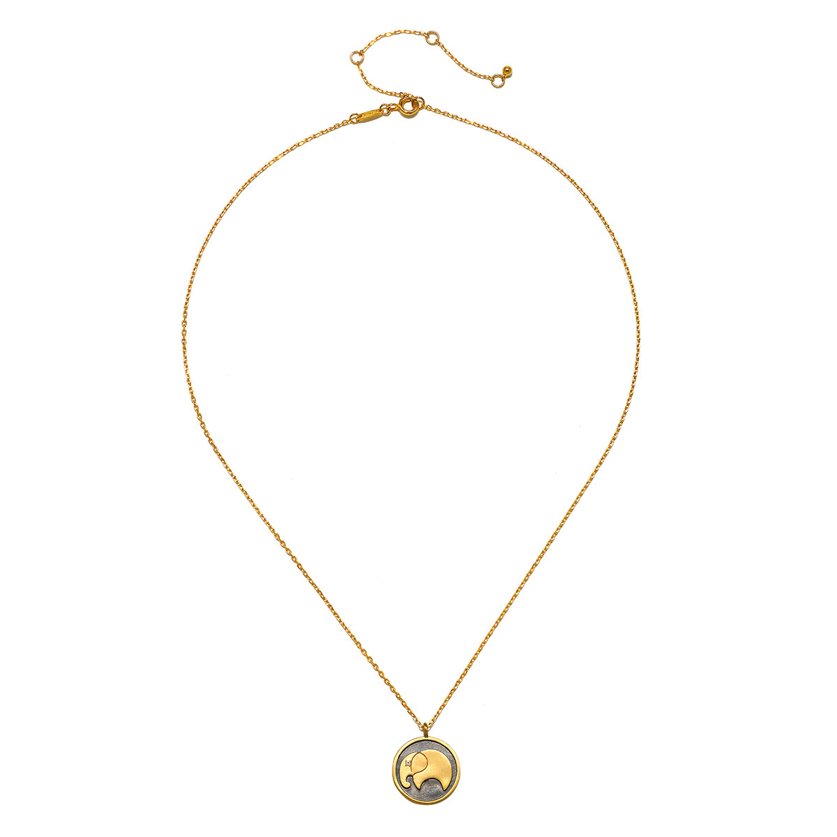 A thin gold chain necklace with an adjustable extender holds a round pendant featuring a gold elephant on a dark background.