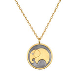 A gold chain necklace with a round pendant showing a gold elephant silhouette with a small clear stone eye on dark gray background.