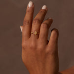 Gold-toned adjustable ring with hamsa and evil eye charms worn on middle finger.