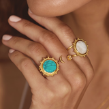 A close-up of hands adorned with various rings including the Spirit in Transformation Lotus Moon Ring, which features a small crescent moon and a lotus. This beautiful spiritual jewelry serves as a talisman for protection and is ideal for yoga practitioners and those seeking meaningful charms that enhance their meditation and zodiac connection.