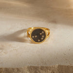The Shine in Sisterhood Constellation Ring features an 18kt gold plated design with a gunmetal background and seven sparkling pyrite stars, symbolizing connection and sisterhood in spiritual jewelry. This unique piece serves as a talisman for meditation and meaningful manifestation, embodying the essence of zodiac inspirations like the Pleiades. Perfect for yogis seeking spiritual protection and beauty under the sun and moon.