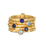 Gold stacked rings with blue, light blue, and purple round gemstones set throughout the bands.