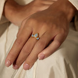 A hand adorned with the Awaken Intuition Labradorite Petal Ring, featuring enchanting labradorite stones set in 18kt gold plate. This piece embodies spiritual significance, making it a perfect choice for meditation, manifestation, and personal protection.