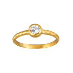 Gold ring with round clear crystal stone set in bezel setting on brushed band.