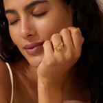 Gold butterfly ring with clear stone center worn on model's hand.