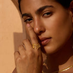 Gold-toned ring with petal-shaped white topaz stone worn on finger.