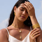 Gold petal ring with white topaz stone worn on model's hand.