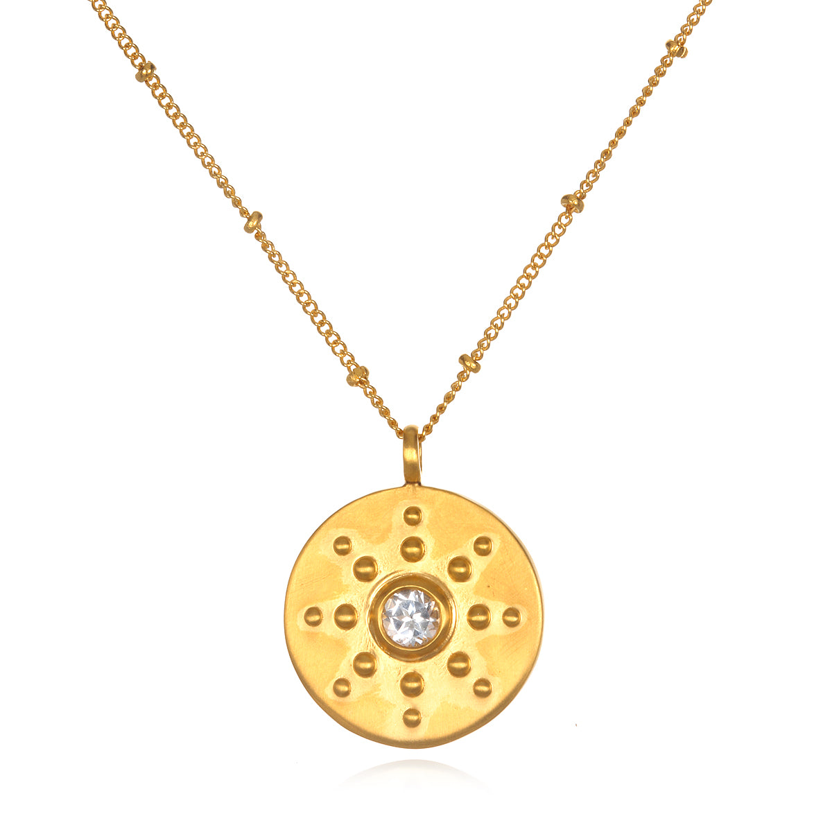 Gold-tone coin pendant with white topaz center stone and decorative studs, suspended from gold chain.