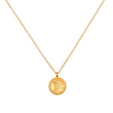 A gold-toned necklace with a thin cable chain and a small round pendant engraved with a crescent moon and sunburst.