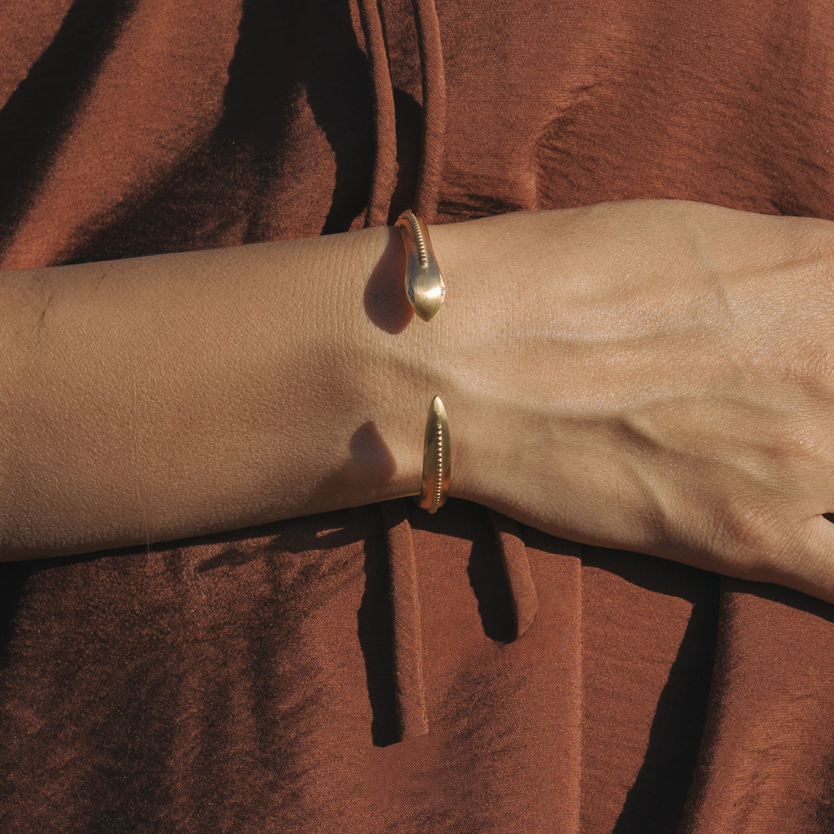 Gold-tone snake cuff bracelet worn on wrist with curved design and textured surface detail.