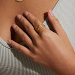 Gold ring with eye motif worn on middle finger with adjustable band design.