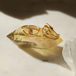 Gold-toned adjustable rings with eye motifs displayed on a faceted yellow crystal stone.