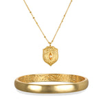 Gold-tone necklace with ornate shield pendant featuring a citrine stone and matching polished bangle bracelet.