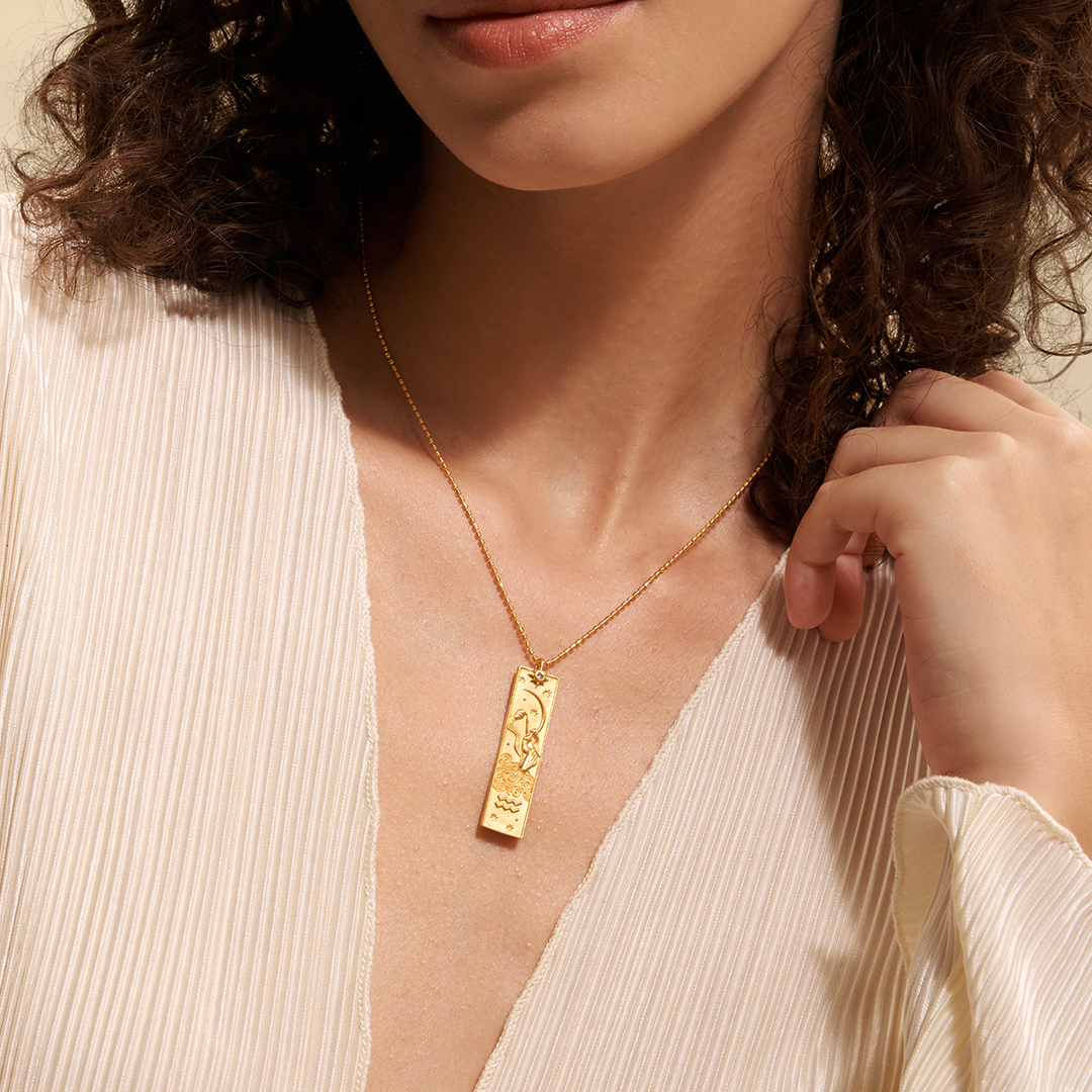 A model elegantly showcases the Story of Aquarius Zodiac Necklace, highlighting the intricate design of the pendant. This spiritual jewelry serves as a protective charm, linking to the zodiac sign Aquarius while inspiring creative energy and a deeper connection to the sun and moon. Ideal for meditation and yoga practices.