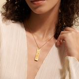 A model elegantly showcases the Story of Aquarius Zodiac Necklace, highlighting the intricate design of the pendant. This spiritual jewelry serves as a protective charm, linking to the zodiac sign Aquarius while inspiring creative energy and a deeper connection to the sun and moon. Ideal for meditation and yoga practices.