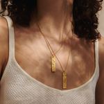A close-up view of the layered Story of Pisces Zodiac Necklace worn by a model. The beautiful gold pendant and white topaz shine as a meaningful piece of spiritual jewelry, embodying the essence of the zodiac, protection, and charm for meditation.