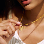 A woman showcasing the Heal your Heart Rose Quartz Dagger Charm on her charm necklace, emphasizing the spiritual jewelry's connection to love, compassion, and meaningful intentions. This golden-accented charm is perfect for meditation, tai chi, and aligning with cosmic energies of the sun and moon.