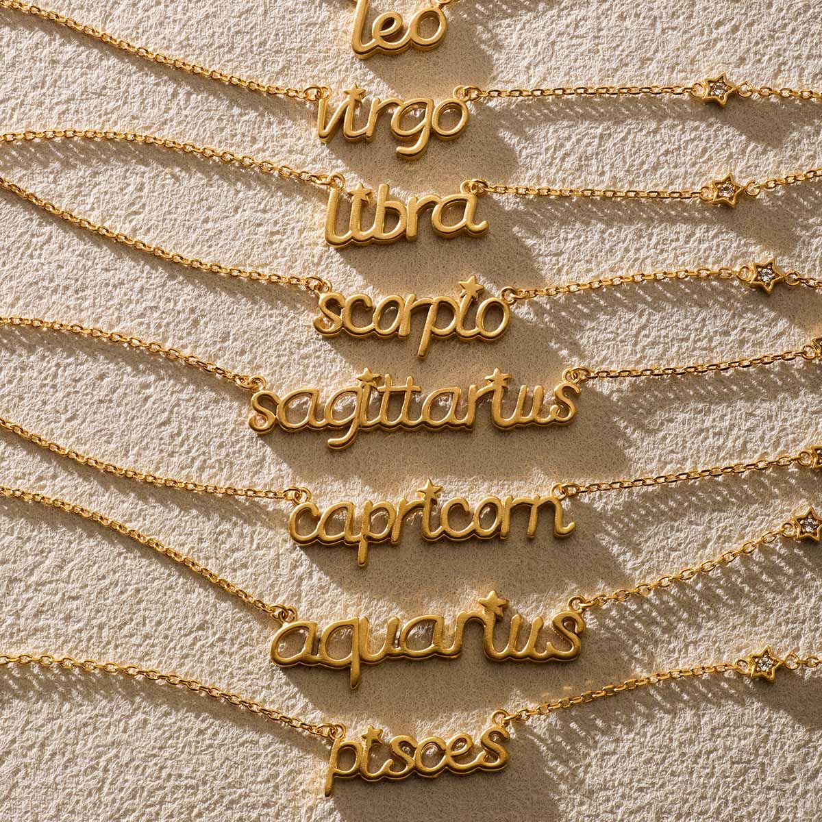 A collection of zodiac script necklaces including the Pisces Intuition Zodiac Script Necklace, representing various signs. Each piece, featuring golden designs, embodies spiritual protection and is perfect for meditation and manifestation.