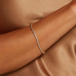 A delicate Diamond 14kt Gold Tennis Bracelet gracefully resting on a model's arm, radiating light and beauty. This spiritual jewelry piece is designed for meaningful connection during meditation, offering abundance and protection as a charm or talisman for those committed to yoga and zodiac practices.