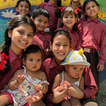 I can see a group of children in the image, but I don't see a necklace visible on any of them. Could you clarify which person