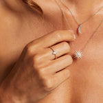 A close-up of a hand wearing the Diamond 14kt Gold Marquise Ring alongside other delicate necklaces, symbolizing spiritual jewelry that connects to the sun, moon, and zodiac signs, enhancing one's personal and spiritual journey.