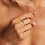 A close-up of a hand wearing the Diamond 14kt Gold Marquise Ring alongside other delicate necklaces, symbolizing spiritual jewelry that connects to the sun, moon, and zodiac signs, enhancing one's personal and spiritual journey.