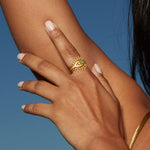Woman's hand adorned with the Shed a Light Evil Eye Ring Set against a beautiful outdoor backdrop, emphasizing the significance of this spiritual talisman for protection and meaningful connections in yoga and zodiac practices.