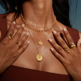Close-up of the Peaceful Buddha Gold Necklace paired beautifully with other gold jewelry, exuding elegance and harmony. This design represents a connection to spiritual practices, making it a perfect accessory for meditation and meaningful gestures.
