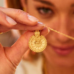 Close-up of a person holding a Gold Mandala Necklace, showcasing its intricate design as spiritual jewelry. This meaningful pendant is perfect for meditation gifts, yoga routines, and serves as a protective amulet imbued with sacred symbolism and manifestation.