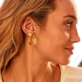 A woman wearing Limitless Stud Earrings Gold alongside hoop earrings, showcasing the intricate mandala design that represents deep meaning and symbolism, ideal for yoga enthusiasts and spiritual practices.