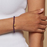 Close-up of the Tranquility Lotus Amethyst Gemstone Bracelet being worn on a hand, showcasing its beautiful amethyst beads, a meaningful addition to spiritual jewelry and meditation gifts, ideal for those seeking protective and sacred energy, enhancing their mantra and yoga journey.