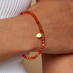 Model wearing the Rooted in Strength Lotus Carnelian Gemstone Bracelet, showcasing its vibrant carnelian beads, ideal for spiritual and meaningful adornments in meditation and yoga.