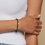 A model wearing the Personal Evolution Lotus Malachite Gemstone Bracelet, showcasing its elegance as a talisman for protection and charm in yoga practices, symbolizing transformation.